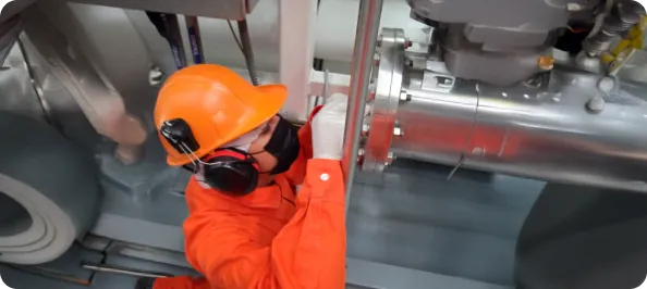 Técnico con casco y protección auditiva revisando un equipo industrial
